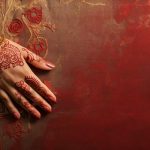 enthralling-banner-displaying-a-woman-s-hand-with-intricate-henna-designs-holding-ethnic-jewelry-against-a-silk-backdrop-generative-ai-photo